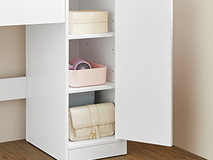 Meuble de rangement blanc avec étagères ouvertes contenant un panier rose et des sacs de couleur claire, faisant partie d'un meuble plus grand