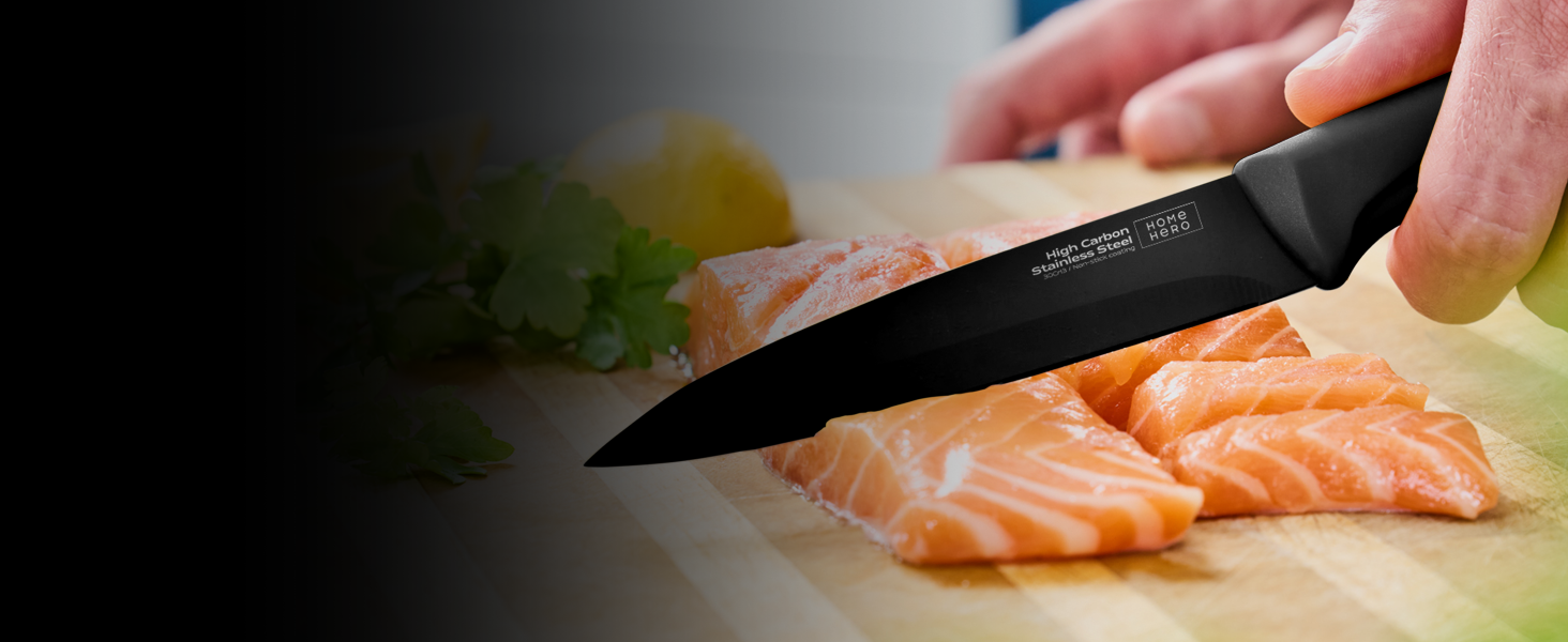 avec manche noir tranchant un filet de saumon cru sur une planche à découper en bois. Fond flou avec des herbes et du citron visibles.