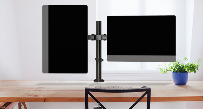 Bras à double écran monté sur un bureau, supportant deux écrans noirs. Fond de mur blanc avec une petite plante visible.