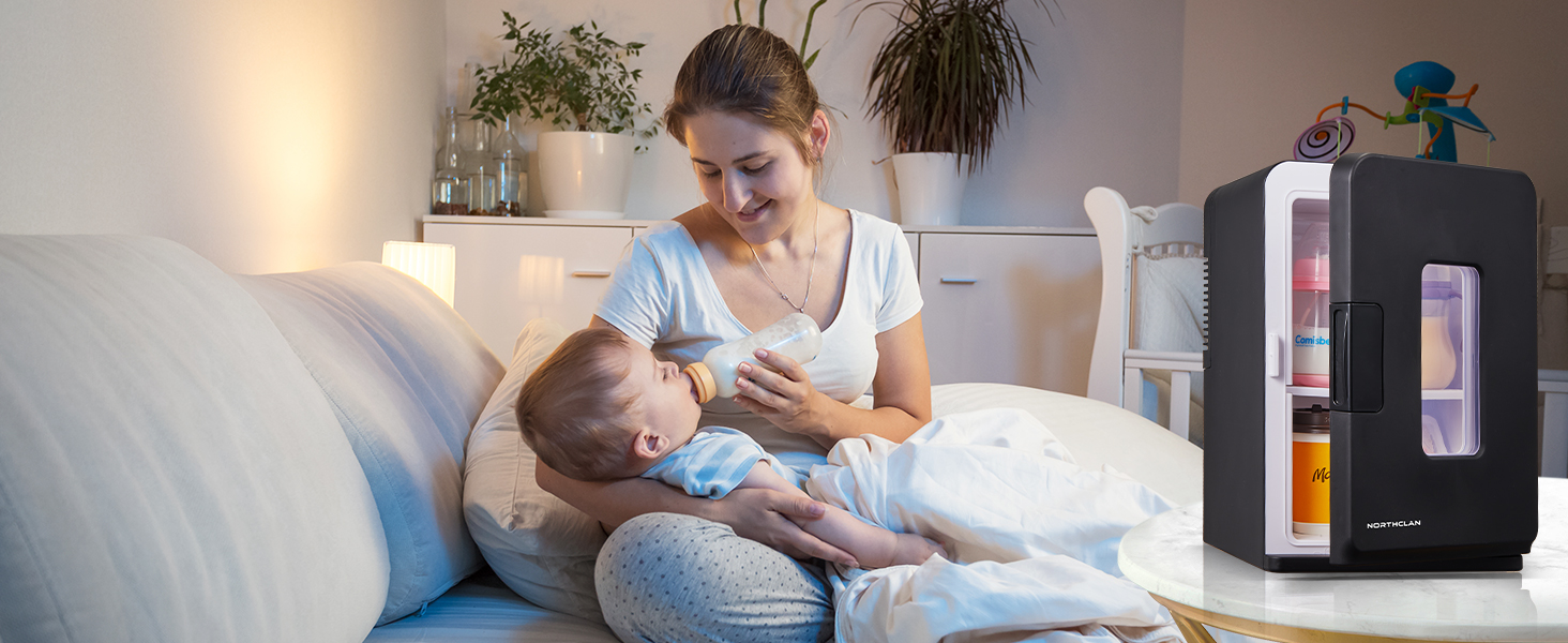 Mini-réfrigérateur compact avec porte vitrée, affichant les boissons. Au premier plan, personne assise sur un divan en train de nourrir un nourrisson