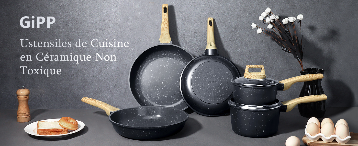 Ensemble d'ustensiles de cuisine en céramique noire non toxique comprenant des poêles à frire, une casserole et une marmite. Poignées et ustensiles en bois. Assiette avec du pain et des œufs au premier plan.