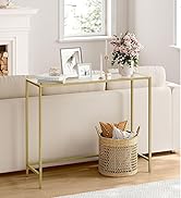 à cadre doré avec plateau en verre. Design fin, placé derrière un canapé blanc. Décoré avec un vase de fleurs, un cadre photo et un panier tressé en dessous.