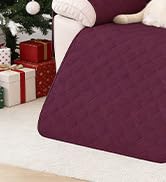 Gros plan d'un tissu texturé bordeaux ou d'un matériau de rembourrage avec vue partielle des objets décoratifs en arrière-plan.