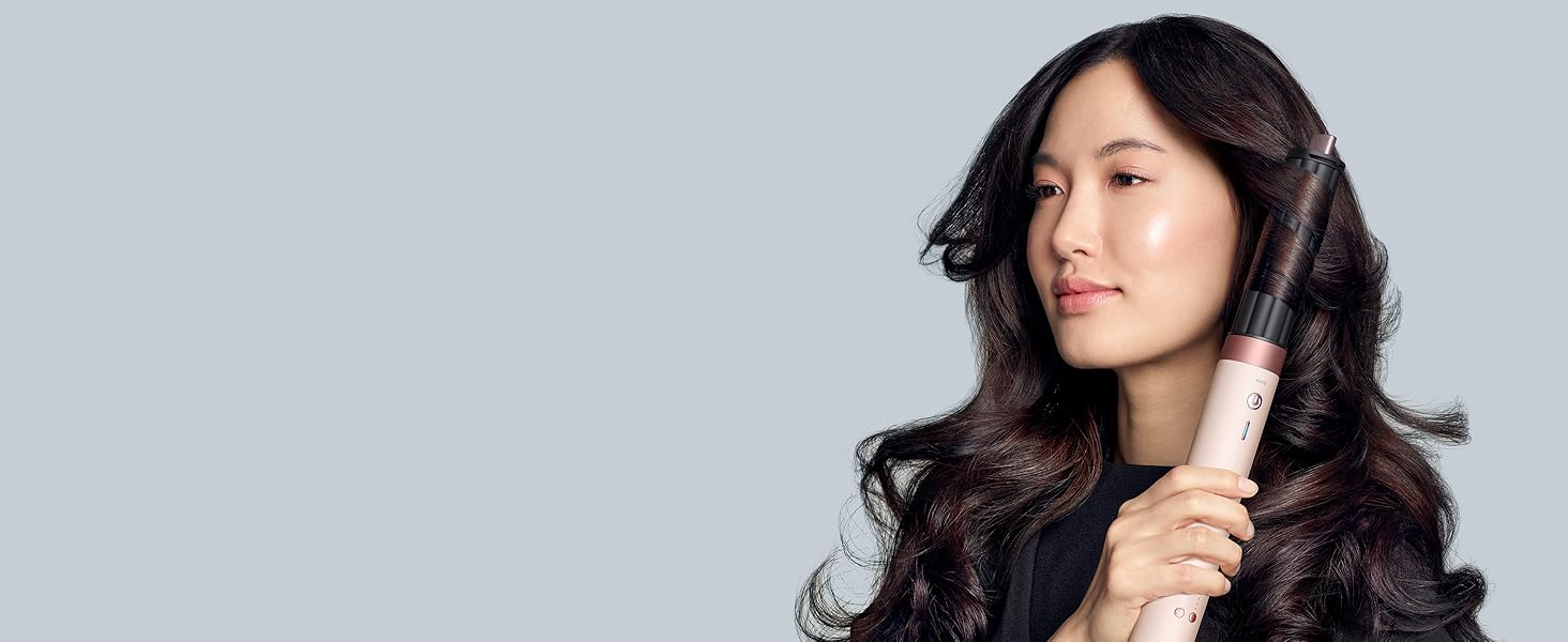 Photo de portrait sur fond gris montrant de longs cheveux ondulés foncés en mouvement.