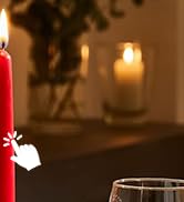 une bougie dans un vase en verre avec des fleurs en arrière-plan.