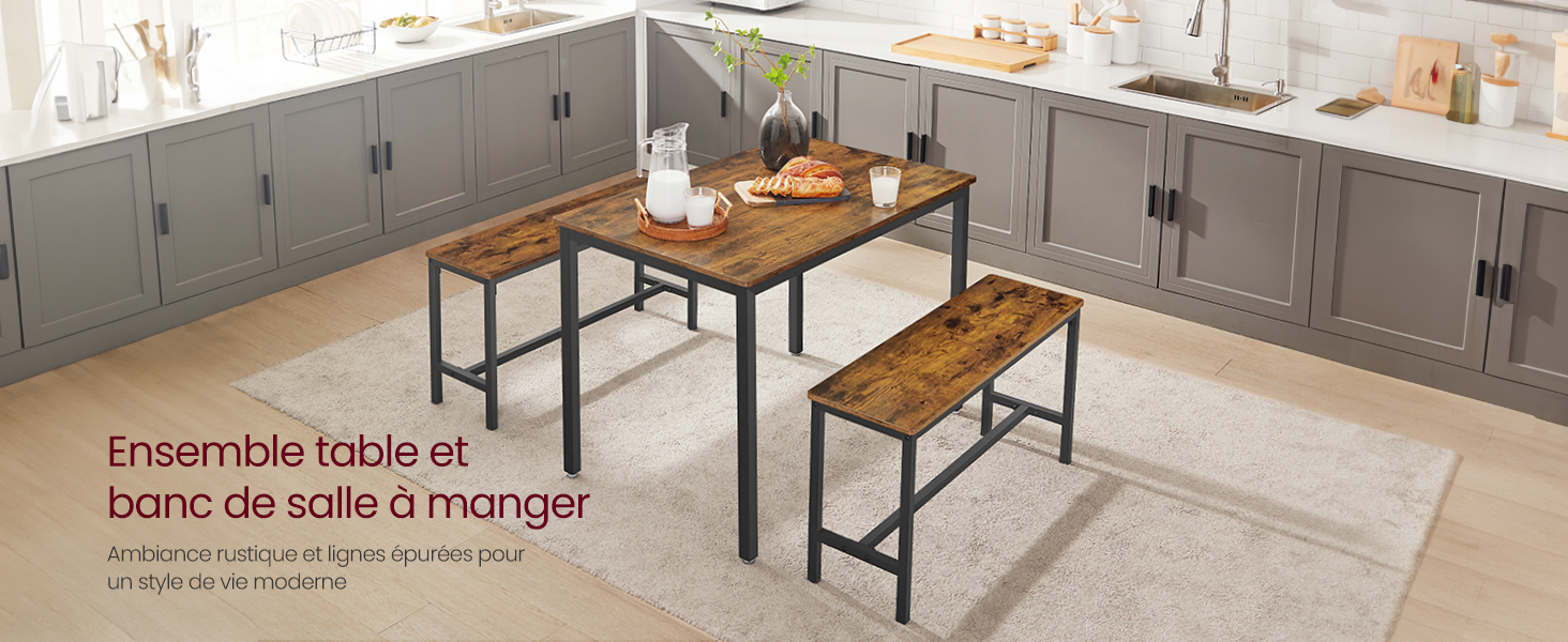 avec table en bois et deux bancs. Montures en métal noir de style industriel. Armoires de cuisine grises visibles en arrière-plan.