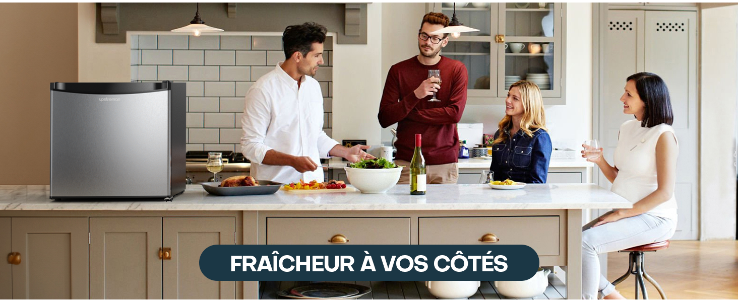 dans un décor de cuisine. Les gens se rassemblent autour d'un comptoir avec de la nourriture et des boissons, démontrant ainsi la commodité de l'appareil pour se divertir