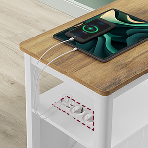 Bureau moderne avec chargeur sans fil intégré sur le dessus. Structure en métal blanc, surface en bois et étagère inférieure. Chargement du smartphone sur tablette.