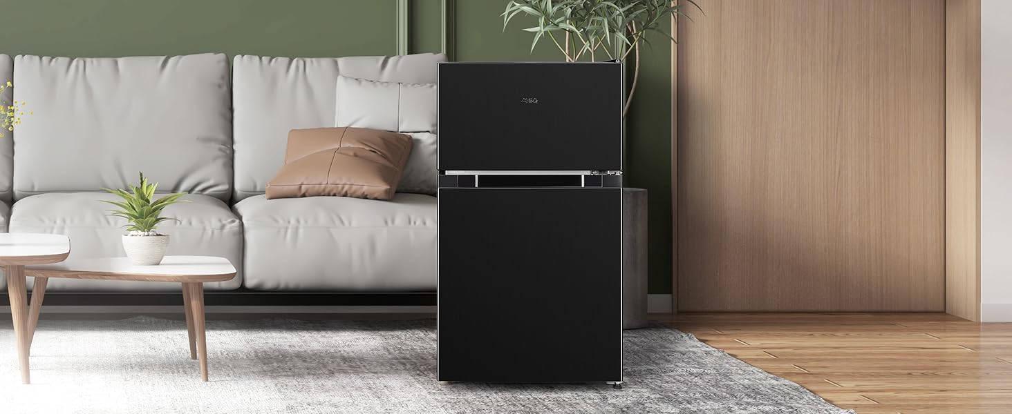 Salon moderne avec canapé gris, table basse et réfrigérateur noir. Palette de couleurs neutres avec des accents en bois et des plantes en pot