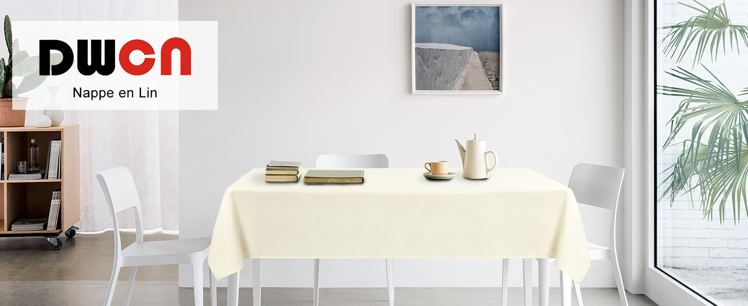 Nappe rectangulaire de couleur crème sur table à manger blanche avec chaises dans un décor intérieur moderne. Une grande fenêtre et une plante en pot sont visibles en arrière-plan.