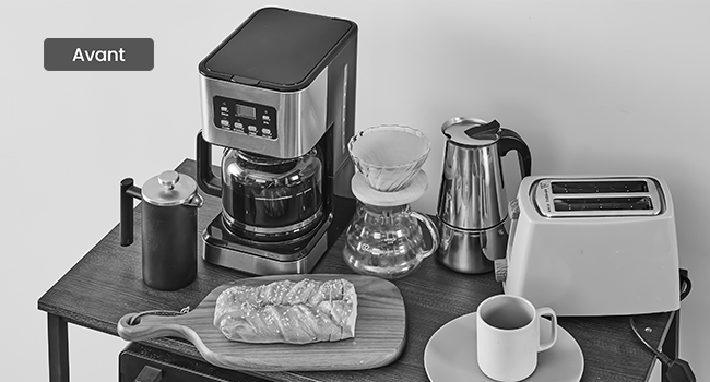 avec appareils électroménagers tels qu'une cafetière, un grille-pain, une bouilloire et du pain. Une tasse et un bocal sont également visibles.