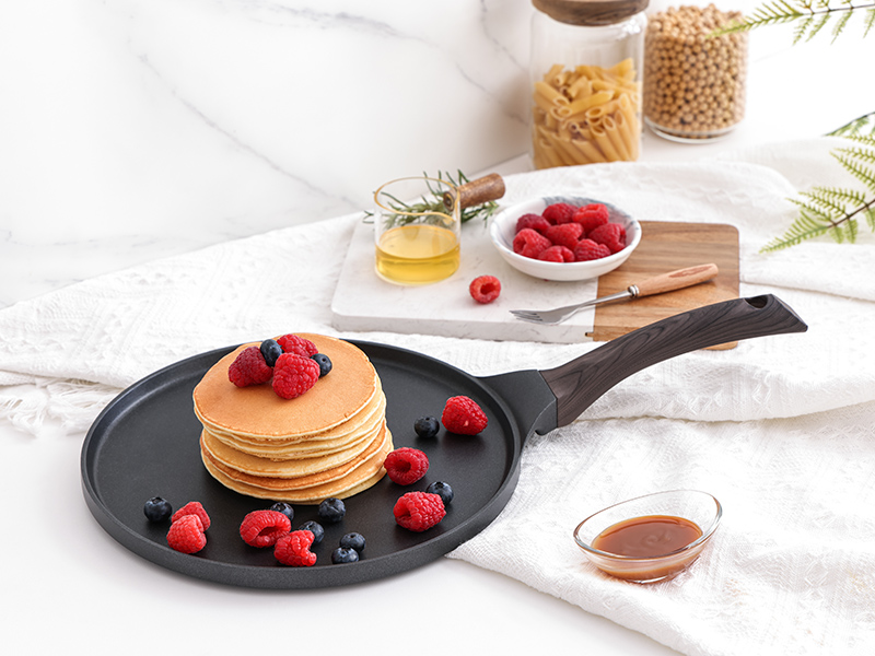 avec une pile de crêpes et de framboises. Planche à découper en bois, sirop et autres ingrédients visibles en arrière-plan.