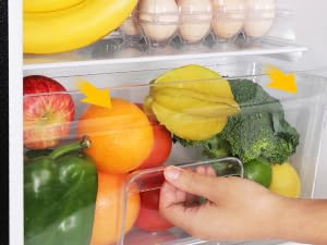 une personne qui cherche un contenant en plastique contenant des fruits et des légumes.