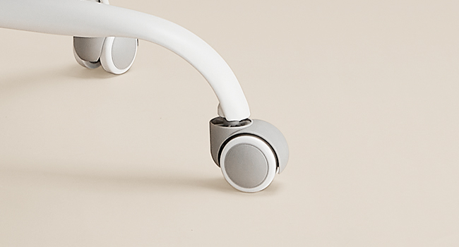 Gros plan de roulettes blanches fixées à une surface de couleur claire, montrant une capacité de roulement fluide