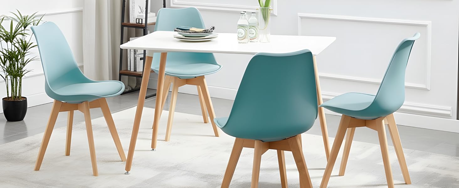 Ensemble de salle à manger moderne composé de chaises rembourrées turquoises avec pieds en bois, disposées autour d'une table blanche dans un intérieur lumineux et minimaliste avec de grandes fenêtres.