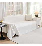 en coton blanc à bords frangés, drapé sur un canapé avec coussin décoratif assorti dans un décor intérieur lumineux