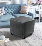 Pouf carré gris ou repose-pieds de rangement avec extérieur en tissu capitonné, présenté dans un salon avec des sièges bleus à proximité