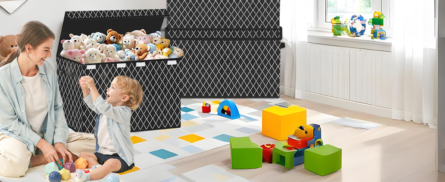 Grand bac de rangement pour jouets en maille noire dans une salle de jeux. Un enfant tend la main dans une poubelle remplie d'animaux en peluche. Blocs colorés et jouets sur le sol. Adulte assis à proximité.