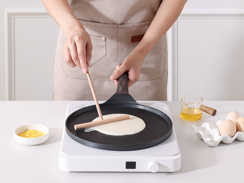 Une plaque chauffante ou une plaque chauffante électrique est utilisée pour cuire une fine crêpe ou une crêpe. Appareil blanc avec surface antiadhésive noire, entouré d'ingrédients